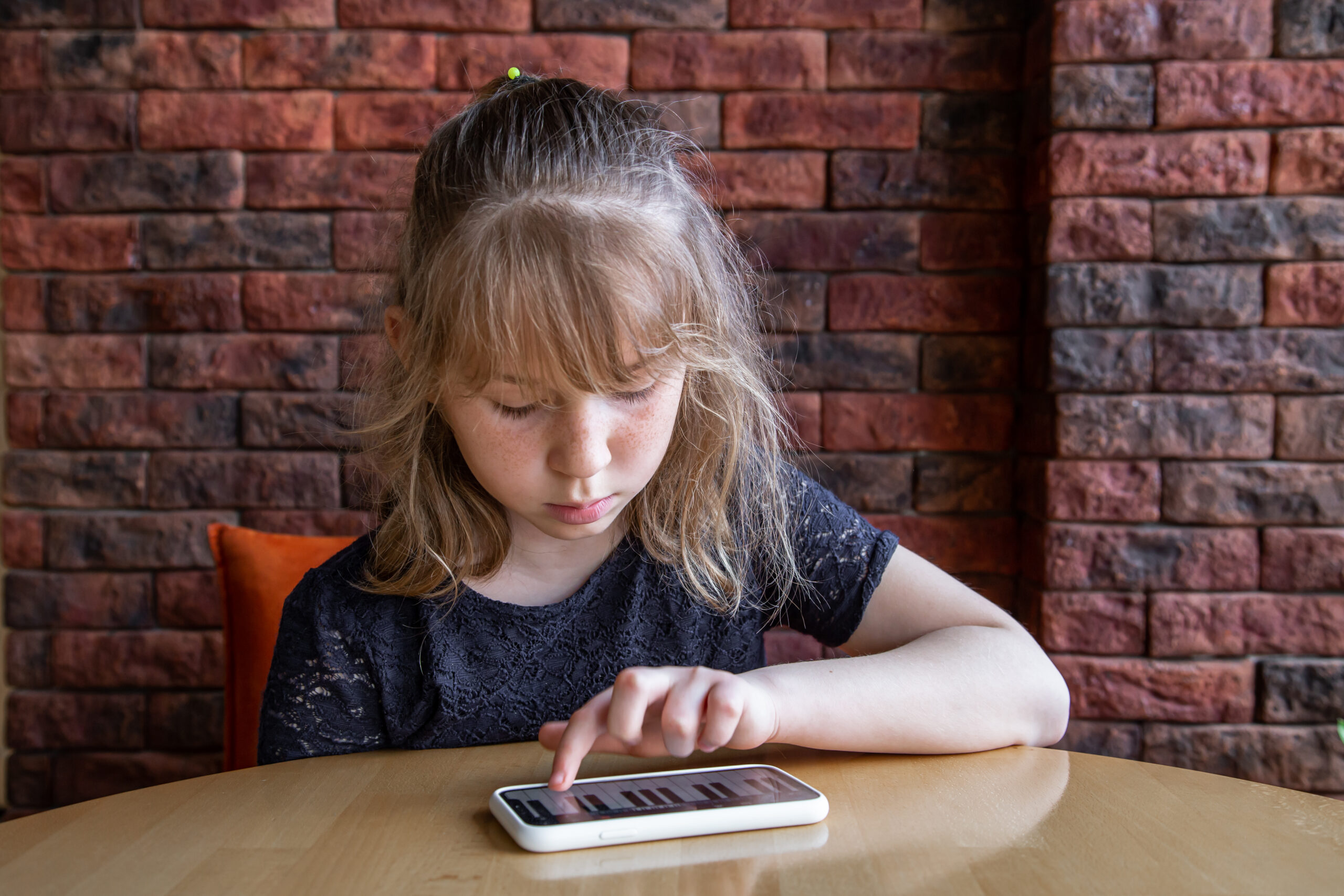 Little girl uses the piano app in the phone.
